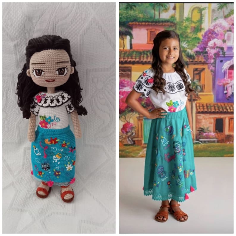 Puede incluir: Una mu&ntilde;eca de crochet que lleva una blusa blanca con bordados negros y una falda turquesa con bordados coloridos. La mu&ntilde;eca tiene el pelo casta&ntilde;o y los ojos marrones. La mu&ntilde;eca est&aacute; de pie sobre una superficie blanca.