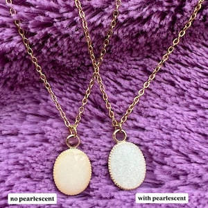 May include: Two gold chain necklaces with oval pendants. One pendant is a creamy color, the other is white and sparkly. Text above reads "Optional Add-on: Pearlescent Powder". Text below reads "no pearlescent" and "with pearlescent".