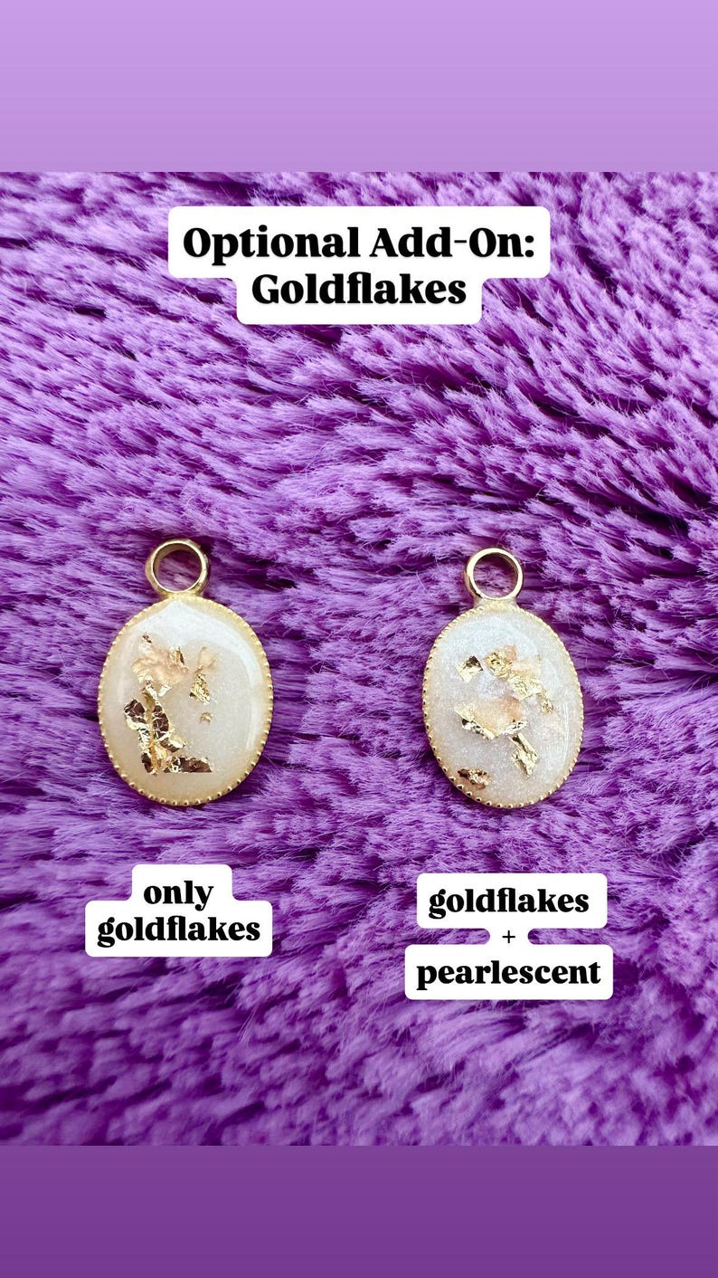 May include: Two oval pendants with gold flakes and a gold-colored border. One pendant is labeled "only goldflakes", and the other is labeled "goldflakes + pearlescent". The background is a textured purple fabric, and the text "Optional Add-On: Goldflakes" is at the top.