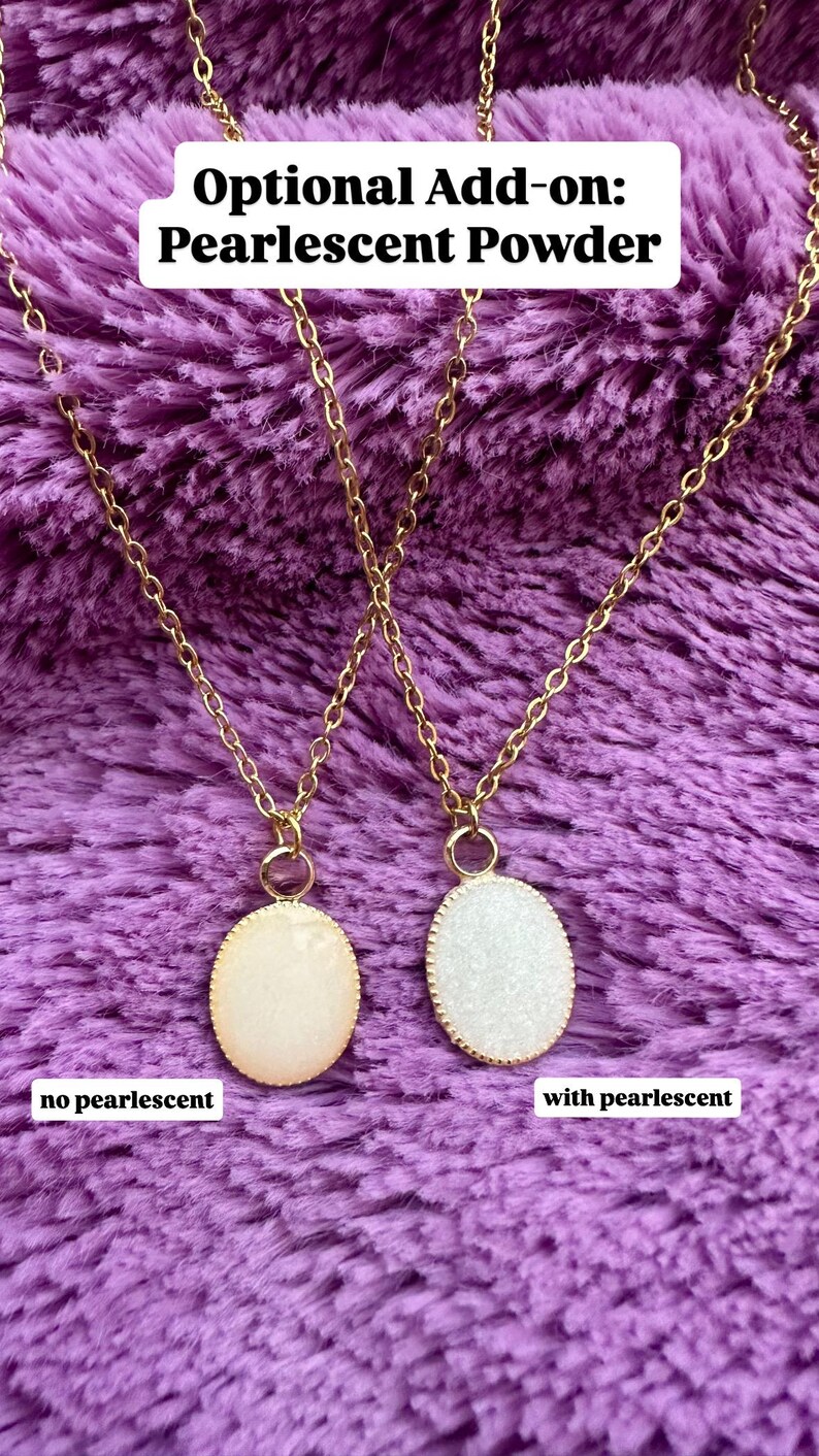 K&ouml;nnte beinhalten: Zwei goldfarbene Halsketten mit ovalen Anh&auml;ngern. Ein Anh&auml;nger ist cremefarben, der andere wei&szlig; und glitzernd. Der Text oben lautet "Optional Add-on: Pearlescent Powder". Der Text unten lautet "no pearlescent" und "with pearlescent".