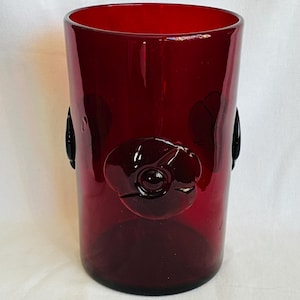 May include: A white ceramic mug with a black handle and the text "But First, Coffee" in a bold, black font. The mug is set against a blurred background, highlighting its clean design.