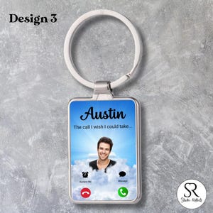 Può includere: Un portachiavi rettangolare argentato con una foto di un uomo di nome Austin su uno sfondo di cielo blu. Il testo "Austin" e "The call I wish I could take..." sono visualizzati. Include un'interfaccia di chiamata telefonica con icone "Remind Me" e "Message".