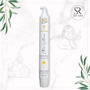 May include: White communion candle with floral and gold cross design. Features the text "GOD BLESS", "Ethan William", "FIRST HOLY COMMUNION", date, and church name. A decorative item for a religious ceremony.