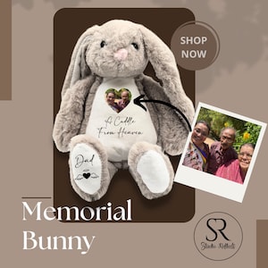 Op de afbeelding: Een zachtgrijs konijn met een witte buik, met een hartvormige foto en de tekst "A Cuddle From Heaven". Het konijn heeft "Dad" op één voet gedrukt. Rechts is een familiefoto te zien. De woorden "Memorial Bunny" staan onderaan.