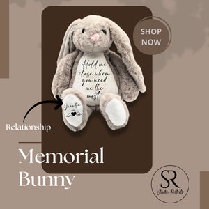 Può includere: Un coniglietto di peluche grigio con lunghe orecchie e un naso rosa. Il coniglietto presenta la scritta "Hold me close when you need me the most" sul petto. Sul piede del coniglietto c'è la parola "Grandpa" con un cuore e ali d'angelo. L'immagine include anche il testo "Memorial Bunny".