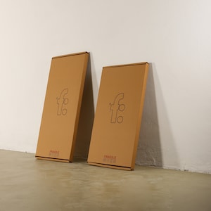 May include: Two brown cardboard boxes with the letter "f" in a circle on the front. The boxes are labeled "Fragile Handle with Care".