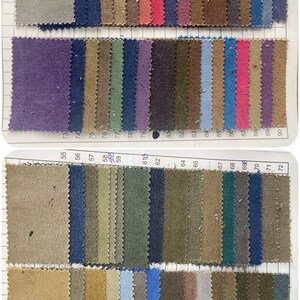 May include: A fabric swatch sample book featuring a grid of rectangular textile pieces in various colors including gray, blue, pink, purple, green, brown, and tan. Each swatch is numbered with printed digits ranging from 37 to 108.
