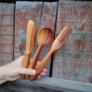 May include: A set of three ceramic mugs with a speckled, matte finish. The mugs are in shades of cream, light gray, and dark gray. Each mug has a simple, minimalist design and a rounded handle.