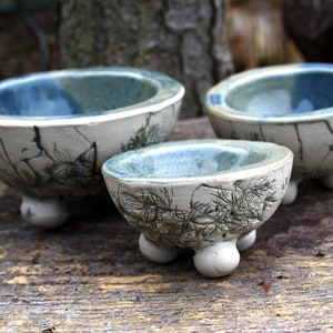 Könnte beinhalten: Drei Keramikschalen mit blauer Glasur und weißer Craquelé-Oberfläche. Die Schalen sind mit einem Blattdesign verziert und haben drei kleine Füße.