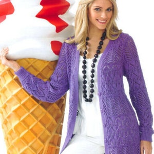 May include: A purple knitted cardigan with a lace pattern and a button closure. The cardigan is long and has a relaxed fit. The model is wearing white pants and a white top.