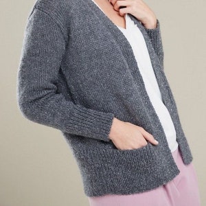 May include: A gray cardigan with a v-neck and pockets. The cardigan is made of a soft, textured fabric.