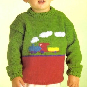 May include: A green knitted sweater with a red and blue train design. The sweater has white clouds above the train and a blue and purple stripe above the red bottom.