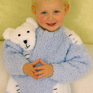 May include: A light blue fluffy sweater with a white polar bear appliqué on the front. The bear has black eyes and a black nose. The sweater has white paw prints on the sleeves and bottom.