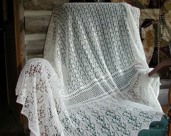 May include: A white crocheted shawl draped over a wooden chair with a green upholstered seat. The shawl has a delicate lace pattern and a scalloped edge.