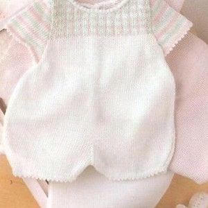 May include: A white knitted baby onesie with pink and green stripes around the neckline. The onesie has short sleeves and a scalloped hem.