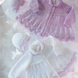 May include: Two knitted baby jackets with matching hats. The jackets are white and pink with a delicate lace pattern. The hats have a scalloped edge.