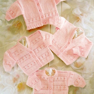 May include: Three pink knitted baby cardigans with button closures. The cardigans have a delicate lace pattern and are made with soft yarn.