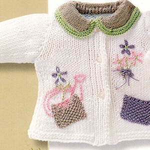May include: White knitted baby cardigan with a brown and green collar, embroidered flowers, and a small purple pocket. The cardigan features a watering can and flowers embroidered on the front.