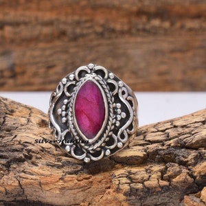 May include: A silver ring with an oval-shaped pink gemstone set in a detailed filigree design.