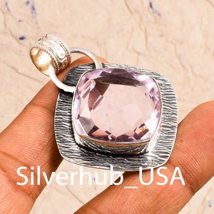 Peut inclure: Un pendentif en argent avec une grande pierre pr&eacute;cieuse facet&eacute;e rose p&acirc;le sertie dans un cadre en argent textur&eacute;. Le pendentif a un b&eacute;li&egrave;re en argent avec un motif d&eacute;coratif.
