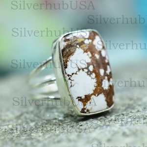 May include: A silver ring featuring a white and brown stone. The stone has a distinctive pattern of brown spots on a white background.