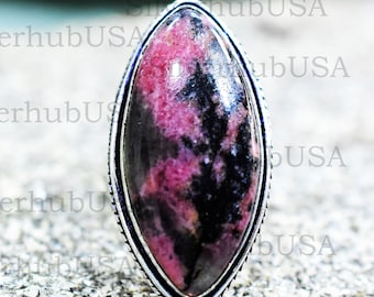 Pode incluir: Um anel de prata com uma grande pedra preciosa oval, de cor rosa e preta. A pedra preciosa tem um padrão de mármore.