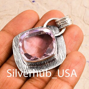 Peut inclure: Un pendentif en argent avec une pierre pr&eacute;cieuse violette clair sertie dans un cadre en argent textur&eacute;. Le pendentif a un b&eacute;li&egrave;re avec un motif orn&eacute;.