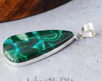 May include: A teardrop-shaped pendant featuring a green and blue malachite stone set in sterling silver.