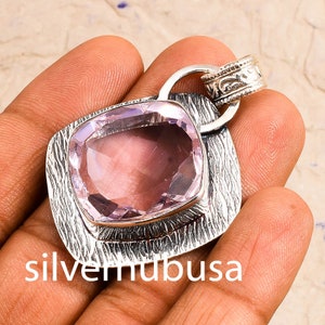 Peut inclure: Un pendentif en argent avec une pierre pr&eacute;cieuse violette clair. Le pendentif a un design textur&eacute; et une b&eacute;li&egrave;re avec un design orn&eacute;.