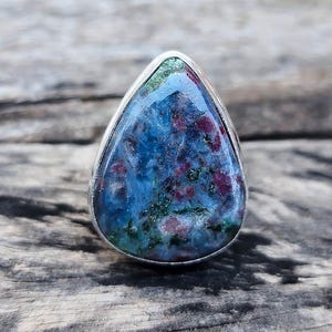 Może przedstawiać: Pierścionek w kształcie łzy z niebieskim, zielonym i różowym kamieniem szlachetnym osadzonym w srebrze.