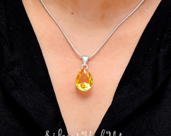 May include: A silver chain necklace with a teardrop-shaped pendant featuring a yellow gemstone.