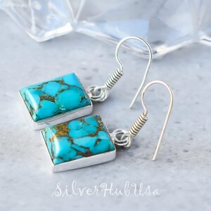 Puede incluir: Un par de pendientes de plata con piedras turquesa. Las piedras son de color azul claro con vetas marrones que las atraviesan. Los pendientes tienen un diseño sencillo y son perfectos para el uso diario.