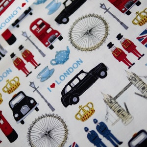 Könnte beinhalten: Weißer Stoff mit einem sich wiederholenden Muster von London-Themen-Illustrationen. Das Design umfasst rote Doppeldeckerbusse, schwarze Taxis, Kronen, die Flagge des Union Jack und den Text "I ❤️ LONDON" in Blau.
