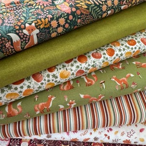 Könnte beinhalten: Ein Stapel verschiedener Stoffmuster mit herbstlichen Designs. Die Stoffe zeigen Drucke mit Füchsen, Eulen, Kürbissen und Herbstlaub in Grün-, Orange-, Braun- und Weißtönen. Einige Stoffe haben Streifenmuster.