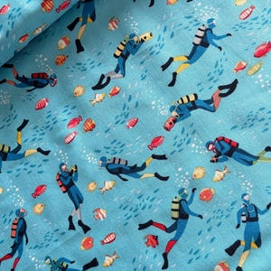 Könnte beinhalten: Hellblauer Stoff mit einem sich wiederholenden Muster von Tauchern und bunten Fischen. Die Taucher tragen blaue Anzüge mit gelben und roten Akzenten und schwimmen zwischen Blasen und verschiedenen Fischen.