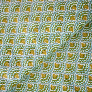 Könnte beinhalten: Nahaufnahme eines Stoffes mit einem sich wiederholenden, fächerförmigen Muster. Das Muster verwendet hellblau, weiß und olivgrün. Der Stoff ist diagonal gefaltet und zeigt die Textur und Details des Musters.