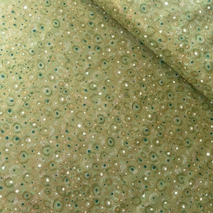 May include: Close-up of a fabric with a repeating pattern of green and white circles and dots on a gold background. The fabric is folded, showing the texture and design. The overall color palette is earthy and natural.