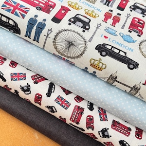 Könnte beinhalten: Nahaufnahme von mehreren Stofflagen mit London-Motiven. Die oberste Schicht hat einen weißen Hintergrund mit schwarzen Autos, roten Bussen, Union Jacks und anderen Londoner Symbolen. Ein hellblauer Stoff mit Polka-Dots und ein dunkelgrauer Stoff sind ebenfalls sichtbar.