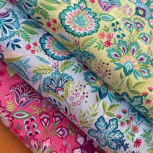 Könnte beinhalten: Nahaufnahme von drei Stoffmustern mit floralen Mustern. Die Stoffe zeigen große, stilisierte Blumen in Türkis-, Rosa-, Lila- und Grüntönen auf hellgelben, hellblauen und rosa Hintergründen. Die Designs umfassen komplizierte Blatt- und Blütenblattdetails.