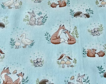 May include: Light blue fabric with a repeating pattern of woodland animals, including foxes, rabbits, ducks, squirrels, hedgehogs, and mice. The illustrations are in a soft, muted color palette with green foliage and butterflies.