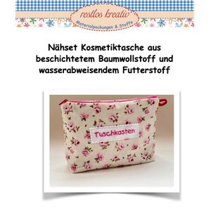 Könnte beinhalten: Eine weiße Kosmetiktasche mit einem rosafarbenen Reißverschluss und einem Blumenmuster. Die Tasche hat ein weißes Etikett mit dem Text "Tuschkasten" in rosa.