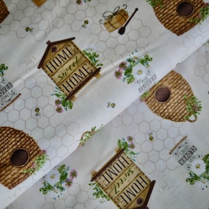 Può includere: Tessuto color crema con un motivo ripetuto di alveari, vasetti di miele, api e il testo "HOME sweet HOME" e "PURE CLOVER HONEY". Il design include accenti floreali e uno sfondo a nido d'ape.