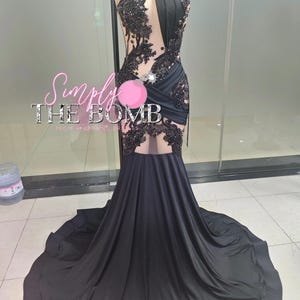 May include: A black formal gown with a halter neckline and a flowing train. The bodice features intricate black lace and beadwork. The text "Simply THE BOMB" is visible on the image.