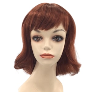 May include: A mannequin head with a short, auburn wig. The wig features a side-swept fringe and gently curled ends. The mannequin has realistic facial features, including brown eyes and a neutral lip color. The background is plain white.
