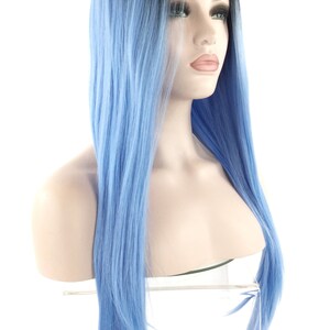 May include: A long, straight wig with a black to light blue ombre effect. The wig is styled on a mannequin head, showcasing the color transition from dark roots to a vibrant blue. The hair appears smooth and sleek, with a natural-looking hairline.