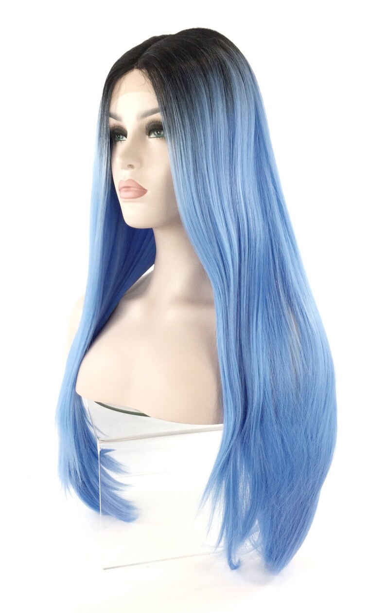 May include: A long, straight wig with a black to blue ombre effect. The wig is styled on a mannequin head, showcasing the vibrant blue color that transitions from the dark roots. The hair is sleek and appears to be synthetic.