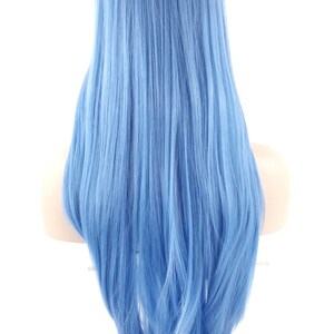 May include: A long, light blue wig with a dark root. The wig is styled with long, straight strands that cascade down the back. The wig is displayed on a mannequin head against a white background.
