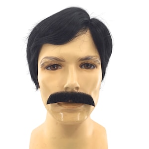 May include: A mannequin head featuring a short, straight black wig with a side-swept fringe and a thick, dark black artificial mustache positioned above the upper lip. The mannequin has light skin, brown eyes, and light brown eyebrows.