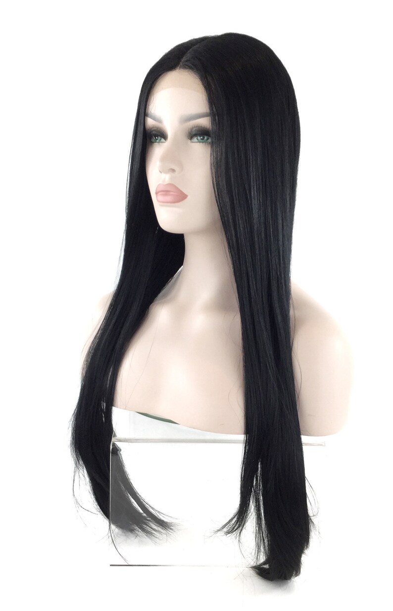 Puede incluir: Una peluca negra con cabello largo y liso se muestra en una cabeza de maniqu&iacute;. La peluca presenta una l&iacute;nea de cabello de aspecto natural y una textura elegante y brillante. El maniqu&iacute; tiene una tez clara y est&aacute; sobre un fondo blanco.