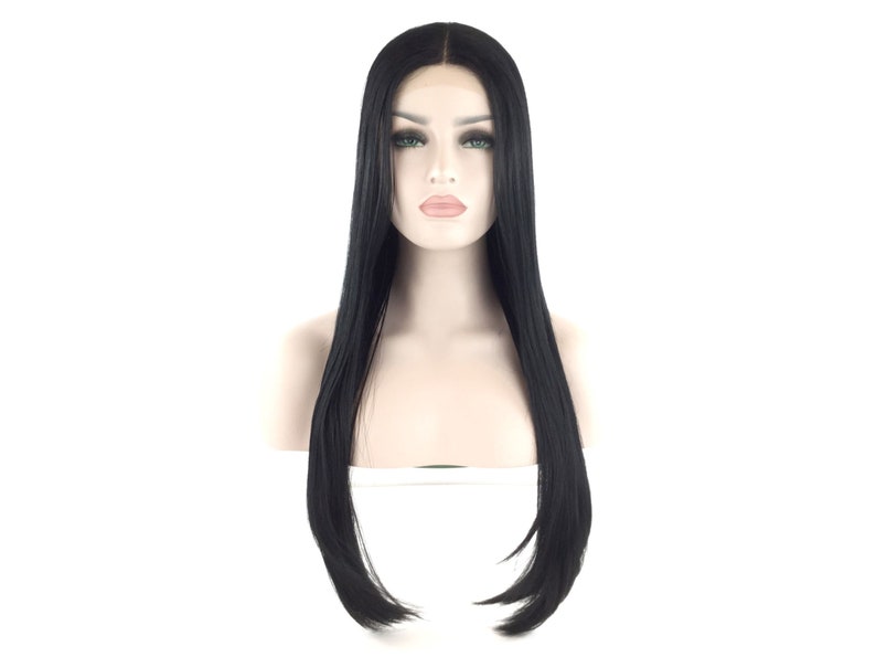 Puede incluir: Peluca negra con cabello largo y liso. La peluca est&aacute; peinada con una raya en medio y llega hasta la mitad del pecho. La peluca se muestra en una cabeza de maniqu&iacute; con tez p&aacute;lida y ojos verdes.